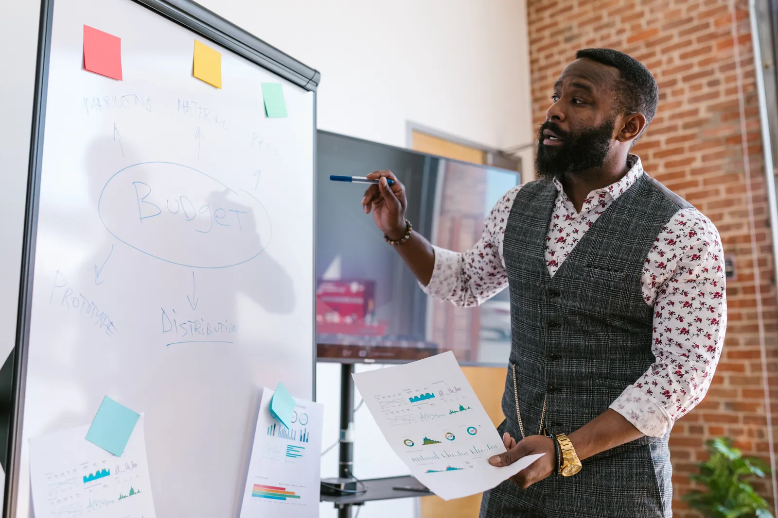 An education leader presenting a strategic plan on a whiteboard to colleagues