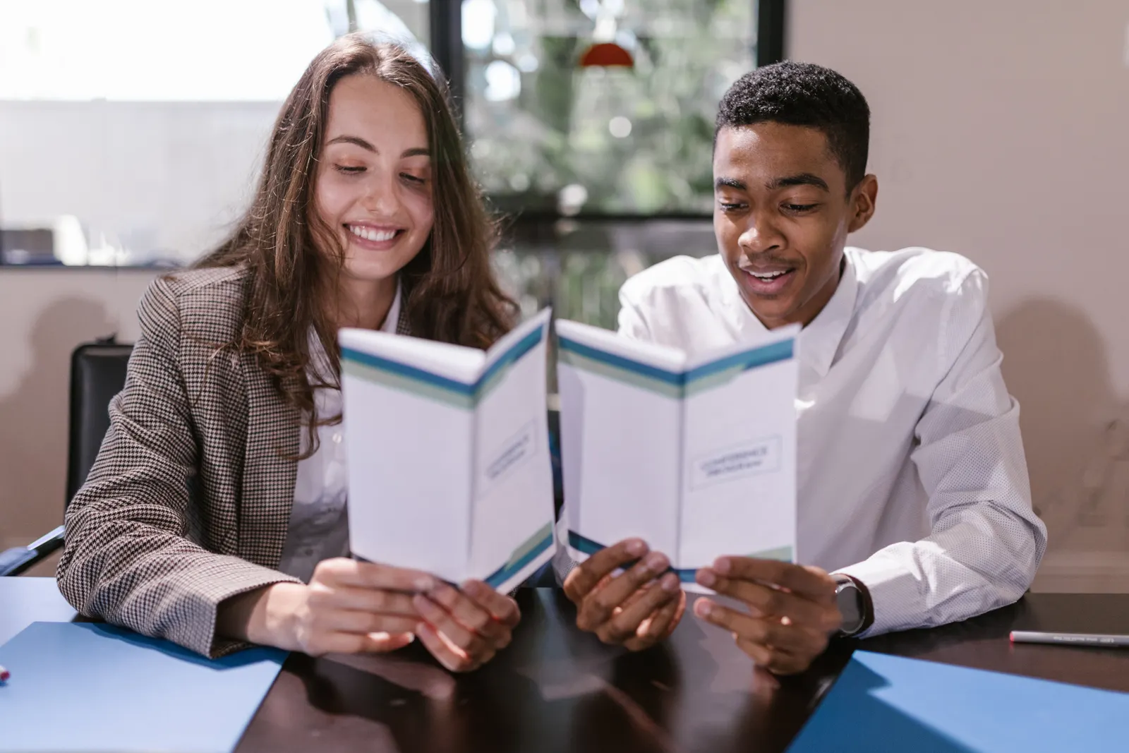 Two education leaders reviewing matching written reports together at a desk